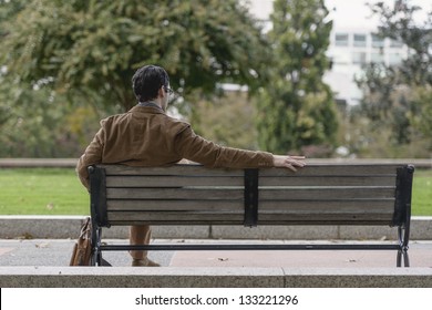 Rear View Of A Man Sitting At Park Bench Waiting