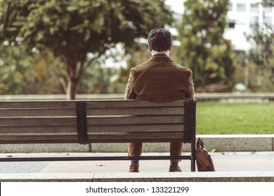 Rear View Of A Man Sitting At Park Bench Waiting