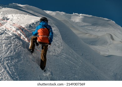 rear view of man in ski suit holding a rope on a mountain slope covered with powdery snow