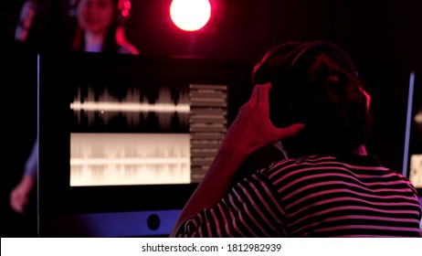 Rear View Man Sound Engineer Working With A Woman Singing While Play Guitar Recording Sound In Studio. Concept Sound Engineer Working In Studio.