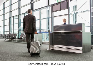 Rear View Of Mature Businessman Walking With His Suitcase On His Gate For Boarding In Airport