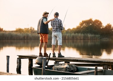 Rear view of mature father and his son fishing from a pier at sunset. Copy space.  - Powered by Shutterstock