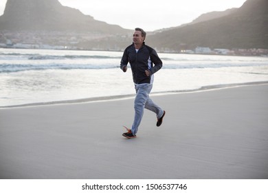 Rear View Of Mature Man Jogging On The Beach