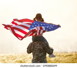 Rear view of military man father carrying happy little daughter with american flag on shoulders and enjoying amazing summer nature view on sunny day, happy soldier dad reunited with kid girl after US  - Powered by Shutterstock