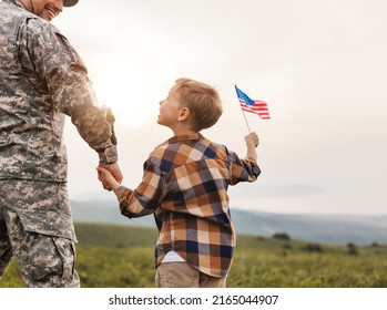 Rear View Of Military Man Father Holding   Son's Hand   With American Flag   And Enjoying Amazing Summer Nature View On Sunny Day, Happy Male Soldier Dad Reunited With Son After US Army