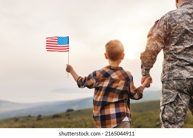 Rear View Of Military Man Father Holding   Son's Hand   With American Flag   And Enjoying Amazing Summer Nature View On Sunny Day, Happy Male Soldier Dad Reunited With Son After US Army