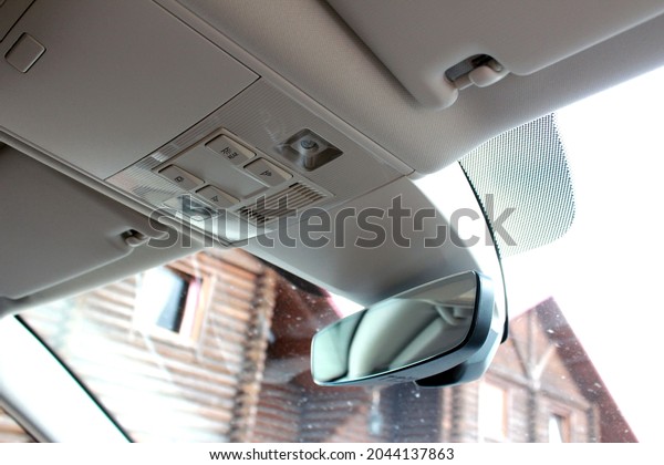 Rear view mirror of a\
car. Rearview mirror with rain sensor and light. Car interior. Car\
driver ceiling
