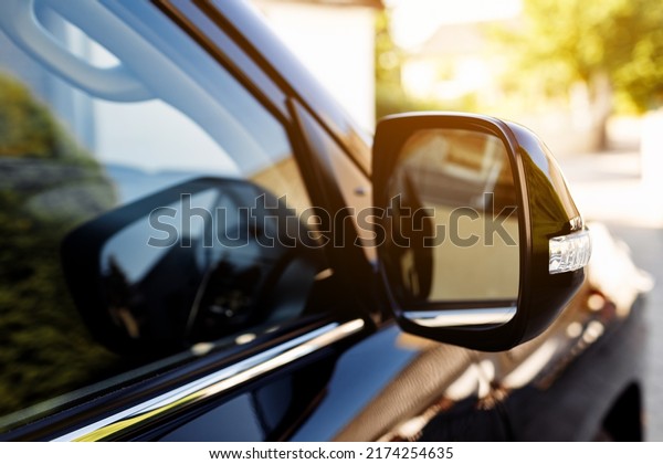 The\
rear view mirror on modern car on a black car. Rear view mirror car\
on the road. Close-up of Road safety while\
driving