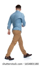 Rear View Of A Motivated Casual Man Walking On White Studio Background