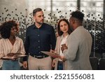 Rear view of multicultural leader standing at enterprise office lobby with his team of professional managers and talking to them. Boss standing in front of group of diverse experts and discussing.