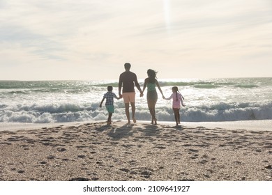 Rear view of multiracial family holding hands walking towards waves in sea at beach on sunny day. lifestyle and weekend. - Shutterstock ID 2109641927