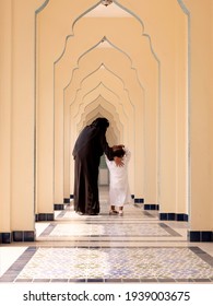 Rear View Of Muslilm Mother In Black Traditional And Hijab With Young Boy Walking Along The Beautiful Corridor.