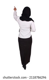 Rear View Of Muslim Woman Wearing Hijab Pointing Forward, Pressing Or Touch Something, Doing Presentation Gesture From Behind, Full Body Portrait