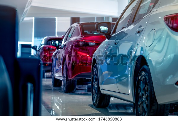 Rear view of new luxury red and white car parked\
in modern show room. Selective focus on white shiny car. Car\
dealership concept. Showroom interior. Automotive industry on\
coronavirus crisis\
concept.