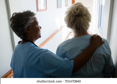 Rear View Of Nurse Senior Woman Walking In Corridor At Nursing Home