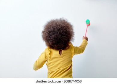 Rear View On Little Child Girl Playing With Plastic Toy, Islated On White Studio Background. African American Black Kid With Fluffy Curly Hair In Yellow Shirt, View From Back - Powered by Shutterstock