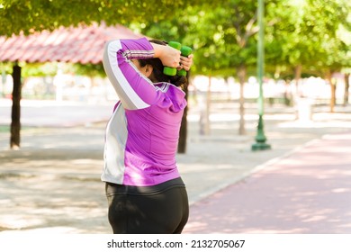 Rear View Of An Overweight Woman Working Out With Dumbell Weights. Determined Woman With A Goal To Lose Body Fat 