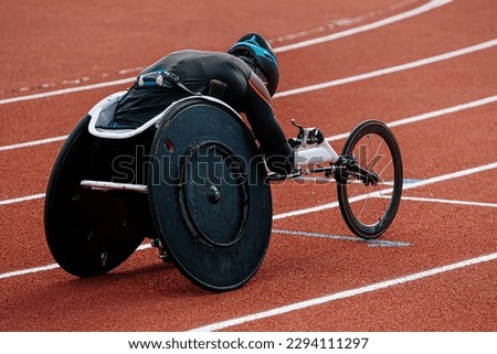 rear view para athlete in wheelchair racing riding on red track stadium, summer para athletics championships