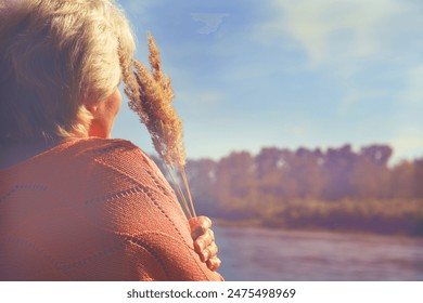 Rear view of a pensive senior woman in the nature, autumn. Lady looking aside pensively. Hello September - Powered by Shutterstock