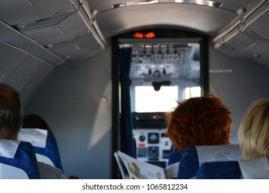 Rear View Of People Sitting And Waiting Airplane To Take Off, Cockpit Door Is Open, Plane Is Still At The Airport, Tallinn Estonia