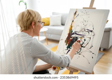Rear view photo blonde short hair creative woman painting easel and brushes in living room 