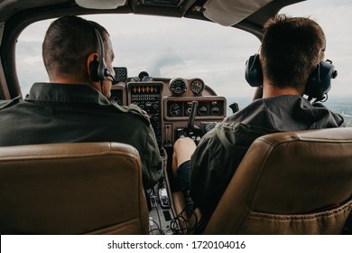 Rear view of pilot and copilot operating controls of private plane. Pilot in cockpit. Aircraft Pilot at work. Rear view of pilots.