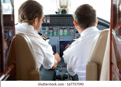 Rear View Of Pilot And Copilot In Private Jet Cockpit