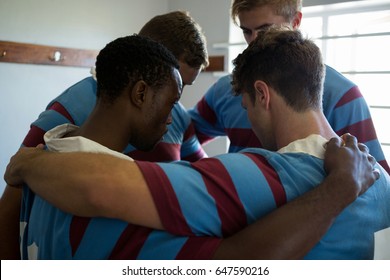 Rear view of player making huddle while standing at locker room - Powered by Shutterstock