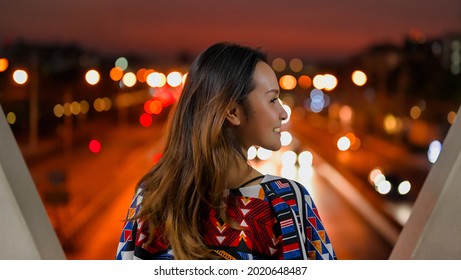 Rear View Point Of Young Women Standing And Show Half Of Her Face In Night Time With Bokeh Of Street Light , Freedom , Inspiration And Motivation Concept