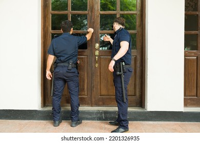 Rear View Of Police Agents With A Search Warrant Arriving To Do A Home Investigation Looking For Criminal Evidence