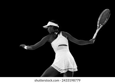 Rear view portrait of focused young woman, tennis player preparing to hit tennis ball against black studio background. Monochrome filter. Concept of women in sport, active lifestyles, energy, movement - Powered by Shutterstock