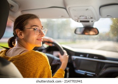 Rear View Portrait Of Young Woman Driver Looking Away While Driving Car In The City