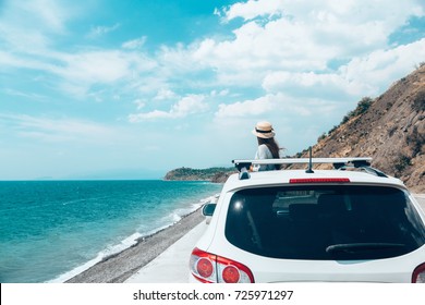 Rear View Of Pre Teen Child In Car Over Sea View On Summer Roadtrip To The Beach 