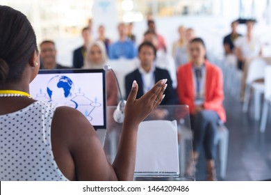 Rear view of pretty African-american female speaker giving speech to diverse people in a business seminar. International diverse corporate business partnership concept - Powered by Shutterstock