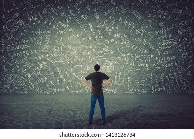 Rear view of puzzled student, hands on hips, stands in front of a huge blackboard try to solve hard mathematics calculation, formula and equations. Project ideas thinking, business planning concept. - Powered by Shutterstock