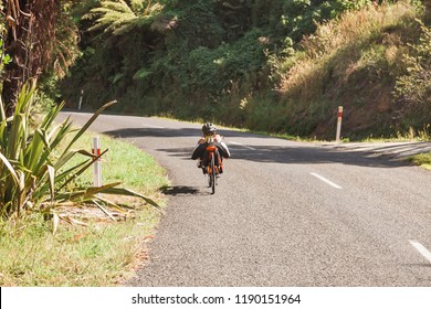 Rear view of recumbent biker driving on country road in Thames, New Zealand. - Powered by Shutterstock