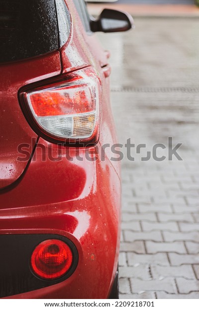 Rear view of\
red car. Red car on the street. Vehicle part. Rear view of\
automobile with bacl light. City transportation. Motor vehicle.\
Tail light of red car. Modern auto\
model.