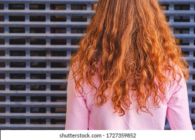 Rear View Of Redheaded Girl Posing In Front Of Metal Grid With Copyspace On It