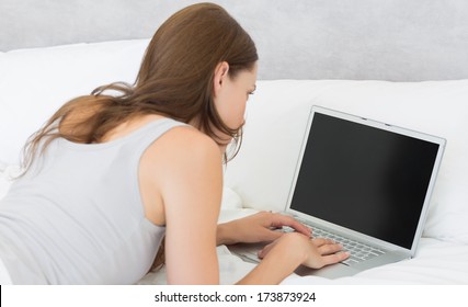 Rear View Of A Relaxed Young Woman Using Laptop In Bed At Home