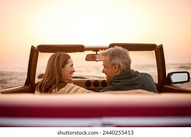 Rear View Of Retired Senior Couple On Vacation In Classic Sports Car At Beach Watching Sunrise - Powered by Shutterstock