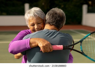 Rear view of romantic biracial senior man embracing smiling wife holding racket at tennis court. romance, unaltered, sport, togetherness, love, retirement, healthy and active lifestyle concept. - Powered by Shutterstock