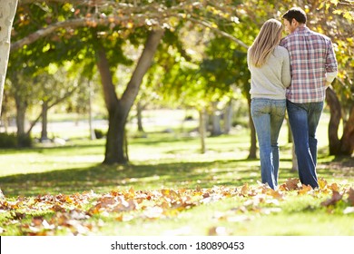 Rear View Of Romantic Couple Walking Through Autumn Woodland