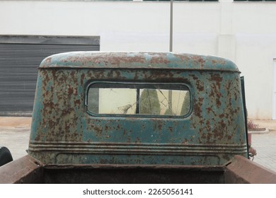 Rear view of the rusty old cabin of a light truck with a cracked window