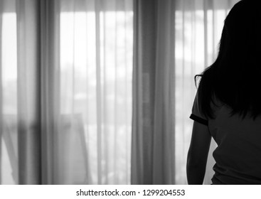 Rear View Of Sad Adult Asian Woman Sit On Bed In Bedroom. Stressed And Depressed Young Woman. Despair Women With Black Long Hair And T-shirts. Lonely And Anxiety. Postpartum Depression Woman. Unhappy.