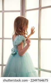 Rear view sad little adorable girl in art azure dress posing near large window indoors, showing excitement. Studio shot unhappy pensive kid lady. Child emotion concept. Copy text space for advertising - Shutterstock ID 2249764675