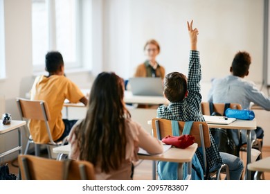 Rear view of schoolboy raising his arm to ask a question during a class in the classroom. - Shutterstock ID 2095783807