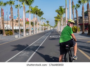 Rear View Of A Senior Bearded Man Enjoying Cycling In The Deserted Sunny Street In Tenerife, Nobody Else,  Lifestyle For A Retired People