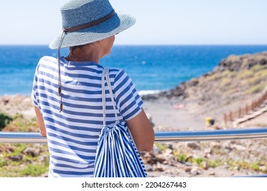 Rear View Of Senior Caucasian Woman In Sea Vacation Looking At The Horizon Over Water