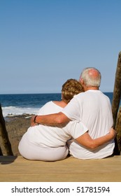 Rear View Of Senior Couple Cuddling On Beach