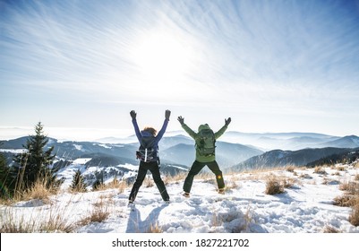 Rear view of senior couple hikers in snow-covered winter nature, jumping. - Shutterstock ID 1827221702